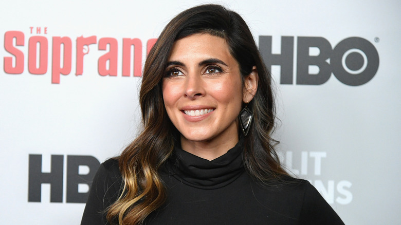 Jamie-Lynn Sigler with The Sopranos logo behind her