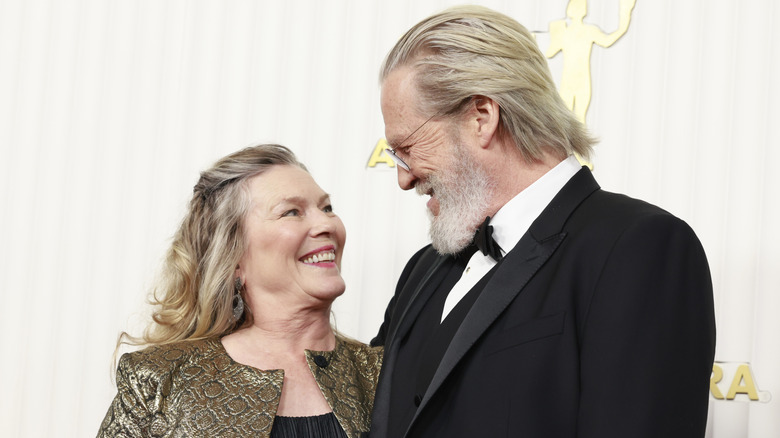 Jeff Bridges and his wife Susan smile at each other while being photographed on the red carpet