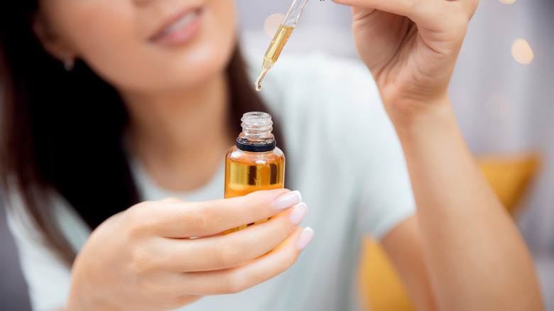 Woman with eyedropper of oil