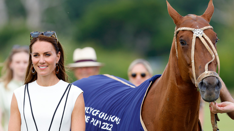 Kate Middleton standing next to a horse