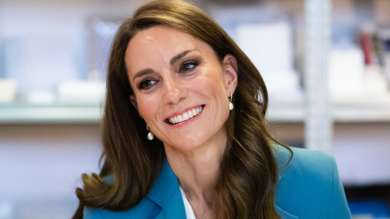 Princess Catherine smiling in a light blue blazer and drop earrings with her hair in loose waves
