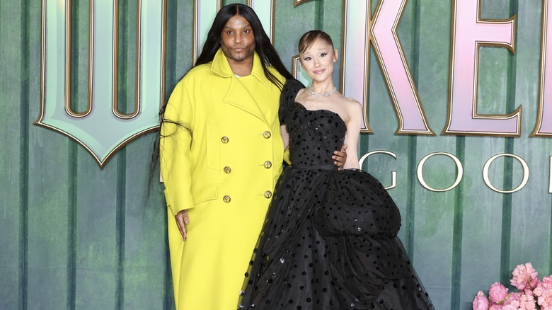 Law Roach in a bright yellow coat, arm-in-arm with Ariana Grande at the "Wicked: For Good" premiere in 2025