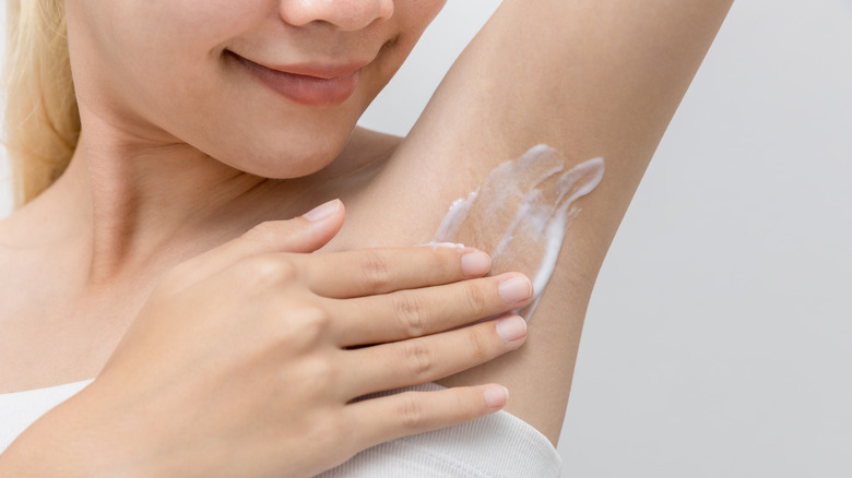 Woman applying cream on armpit