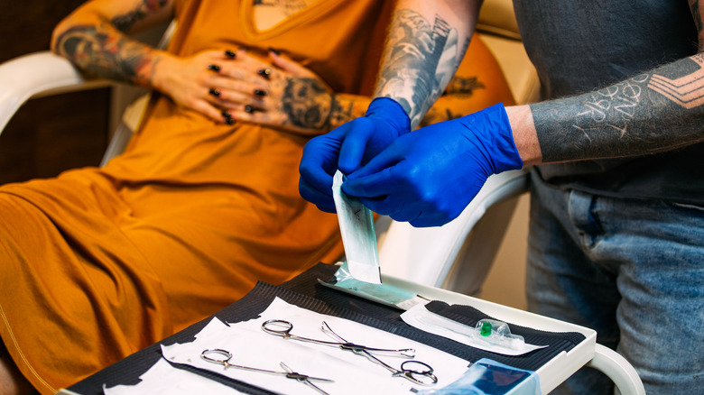 person sitting in tattoo and piercing shop