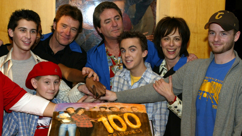 The cast and creator of 'Malcolm in the Middle' standing around a cake