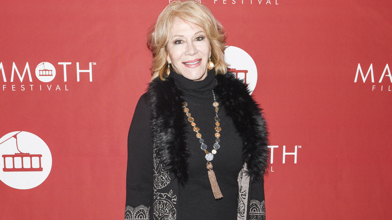 Aissa Wayne standing in front of a red background