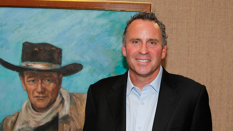 Ethan Wayne standing in front of a painting of John Wayne