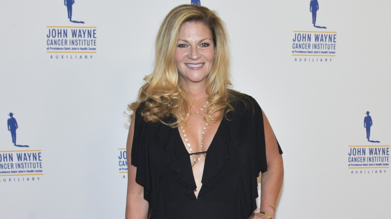 Marisa Wayne standing in front of logos for the John Wayne Cancer Institute