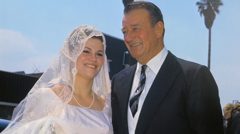 Melinda Wayne Munoz wearing a wedding dress and standing next to John Wayne