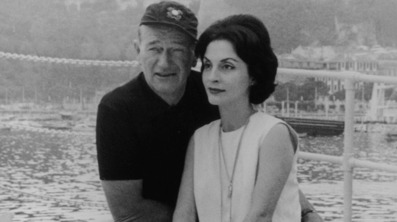 John Wayne and Pilar Pallete standing in front of a harbor