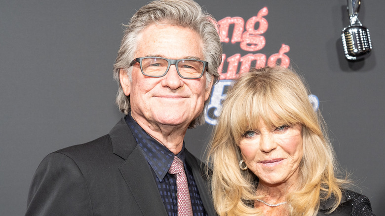 Kurt Russell (L) and Goldie Hawn smiling and posing.