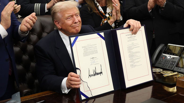 Donald Trump grinning from behind the Resolute desk