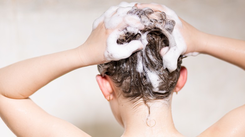 Woman lathering her hair up with shampoo