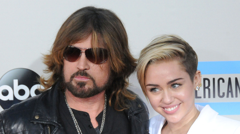 Billy Ray and Miley Cyrus smiling while posing at an event together