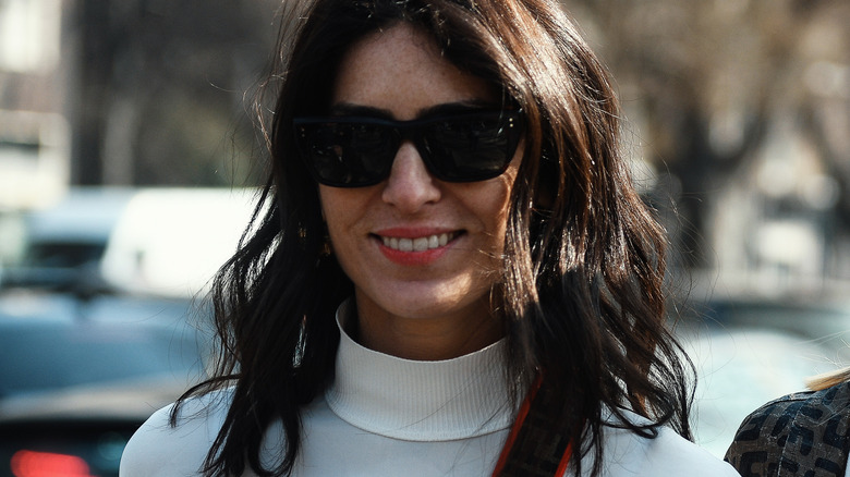 Smiling brunette wearing a mock-neck and sunglasses 