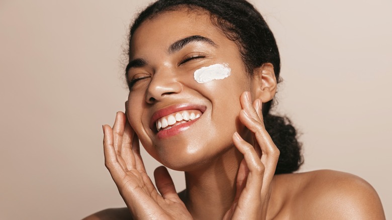 Woman smiling while cleansing her face