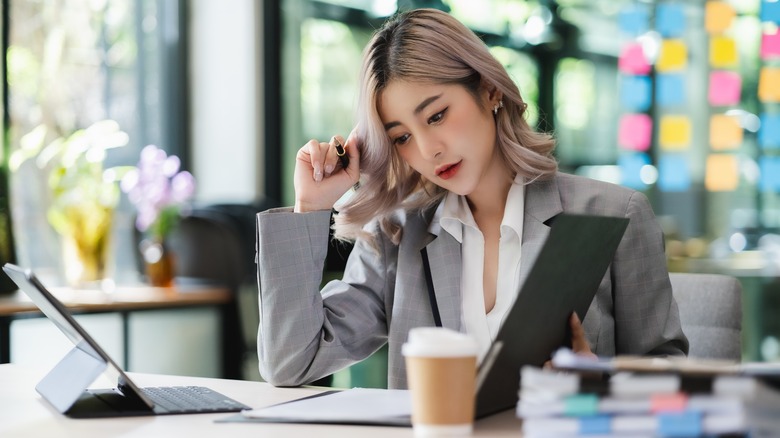 Asian business woman working at desk looking at open file