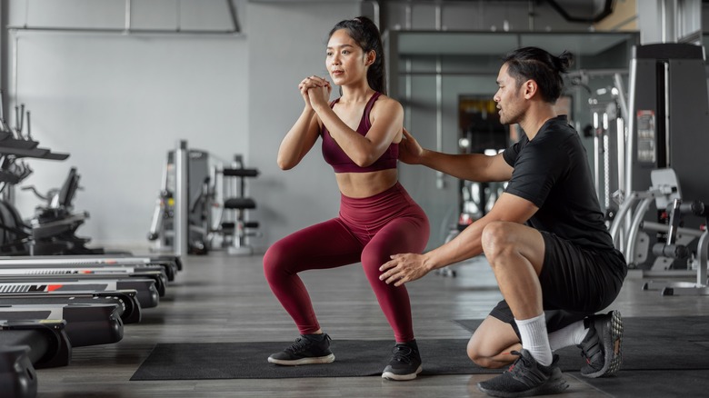 Man assisting woman in gym