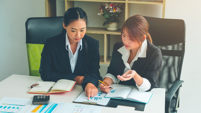 Two Asian women analyzing documents