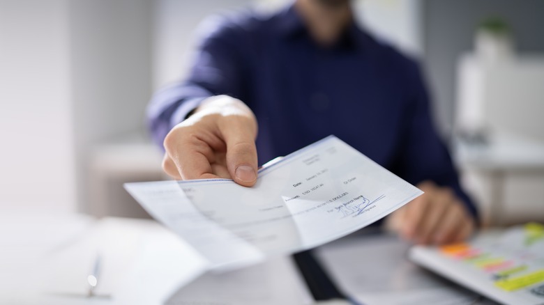 Man handing paycheck