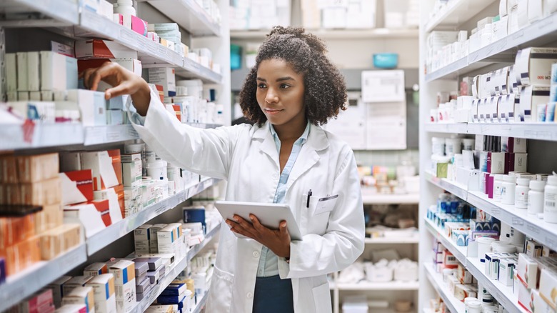 Black female pharmacist reaching for prescription on shelf