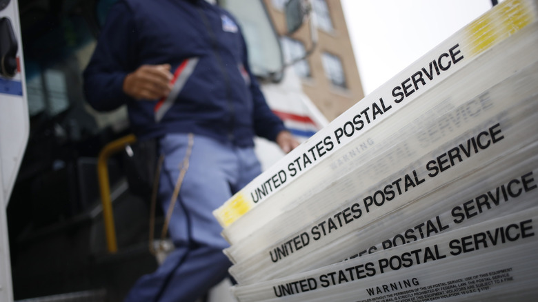 A United States Postal Service postal worker with mail crates