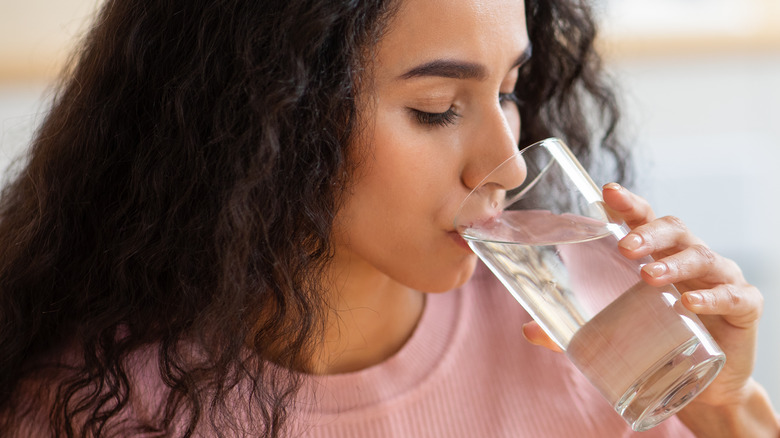 Dark haired woman drinking a glass of water