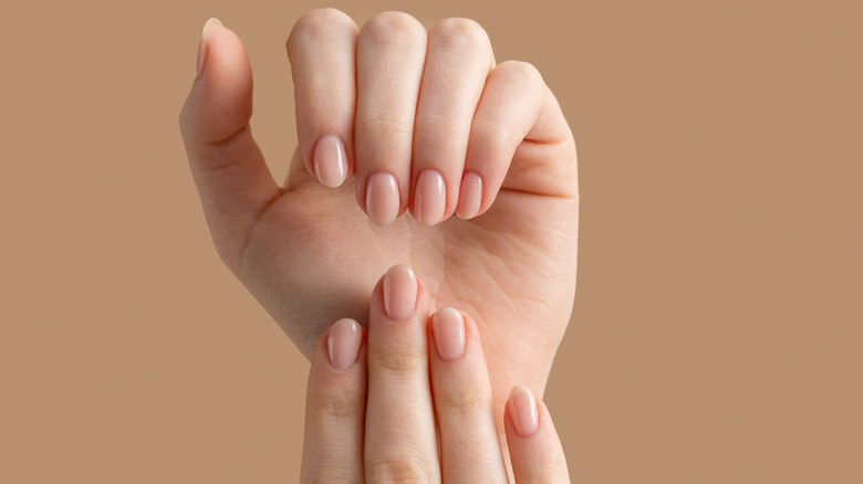 Natural manicured hands on a tan background