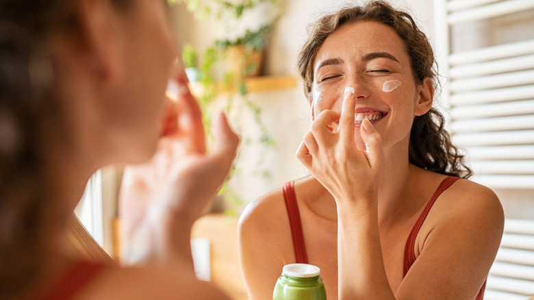 smiling woman putting on moisturizer