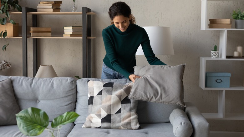 young woman moving pillow on sofa