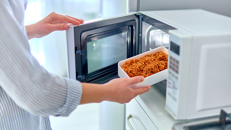 Person puts spaghetti into microwave