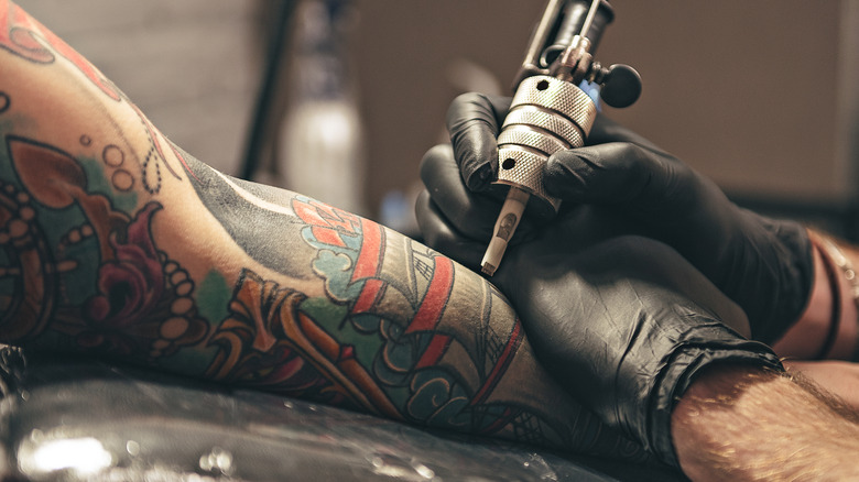 Woman with tattoo sleeve getting a new addition