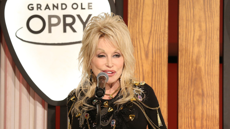 Dolly Parton talking in front of Grand Ole Opry sign