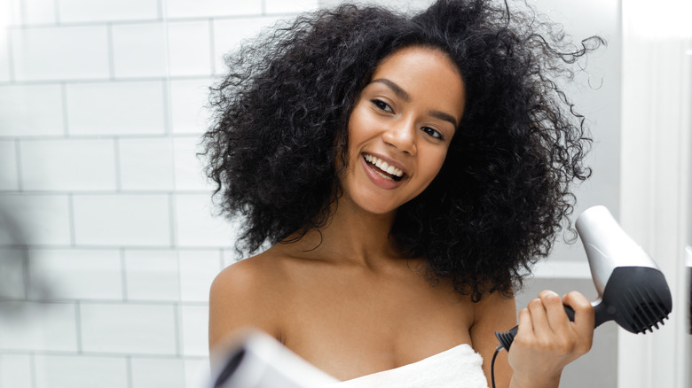Woman smiling while blowdrying hair