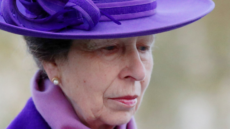 Princess Anne wearing a purple hat looking down