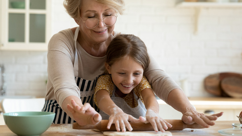 Child working with adult family member in kitchen
