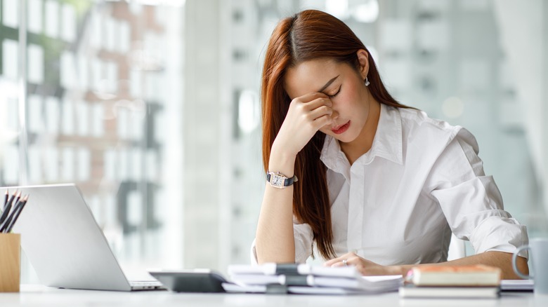 A woman sitting at her desk looking stressed