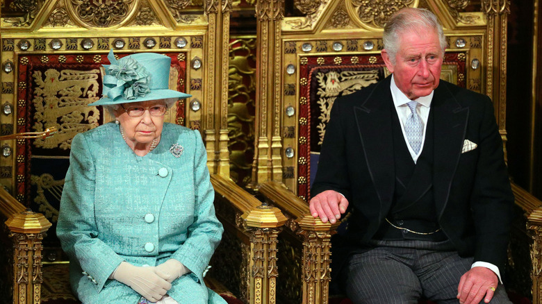 Queen Elizabeth II and Prince Charles sitting on thrones
