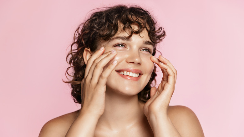 A woman touching her face and smiling 