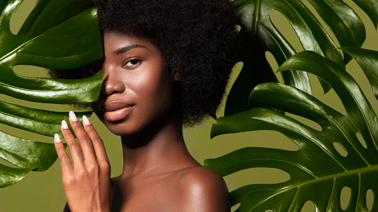 Woman behind a monstera leaf