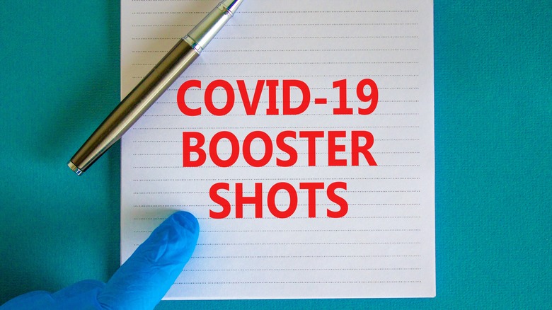 Physician pointing at paper that says "COVID-19 BOOSTER SHOTS"