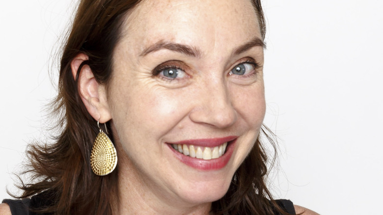 Stephanie Courtney poses in front of a white background with a big smile.