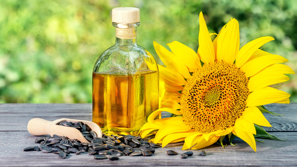 a sunflower, sunflower seeds, and a glass bottle of sunflower oil 