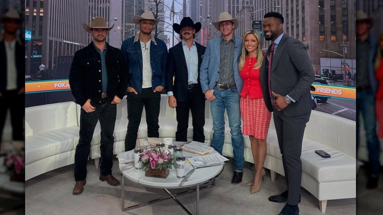 Ainsley Earhardt smiling in a red dress next to Lawrence Jones, who's wearing a suit, and the cast of "Farmer Wants a Wife."
