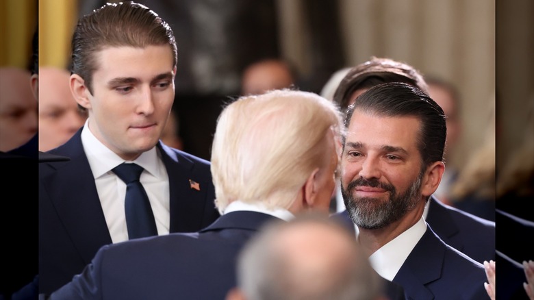 Donald Trump Jr. looking at his father, Donald Trump, with pride as Barron Trump towers over both of them