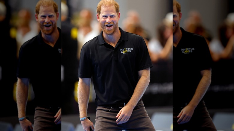 Prince Harry smiling in an Invictus Games polo shirt.
