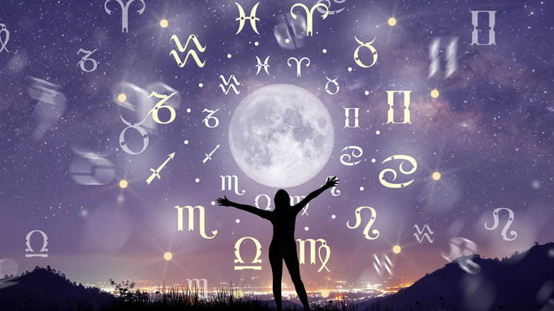 Silhouette of a person in front of zodiac signs in sky