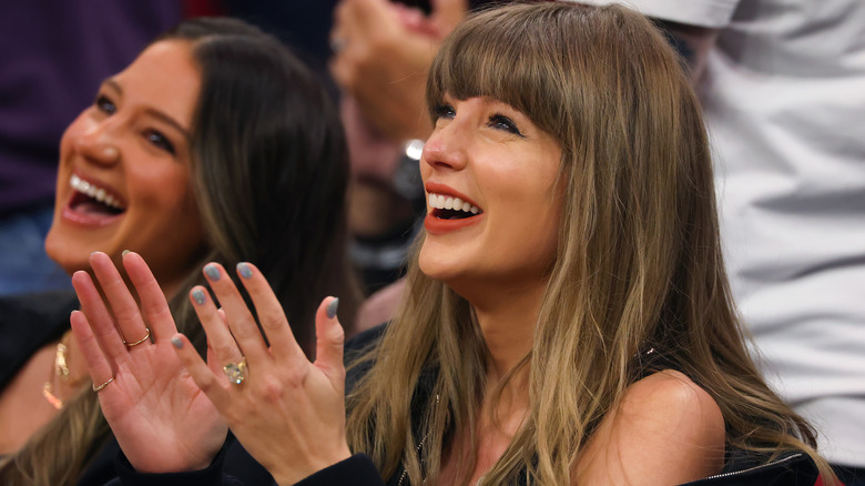 A laughing Taylor Swift applauding