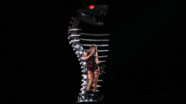 Taylor Swift performing against a serpent backdrop