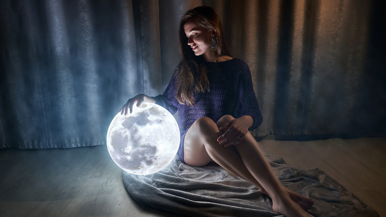 A woman sitting beside and holding a full moon